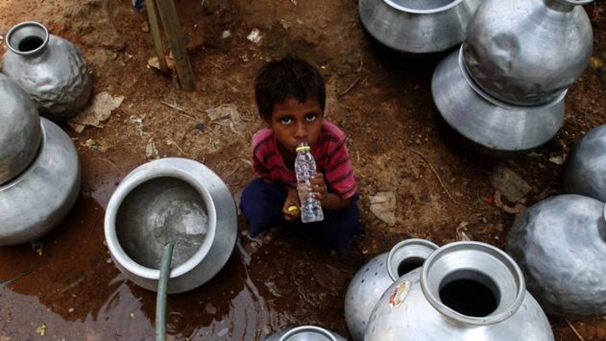 Un niño indio recoge agua en un depósito gubernamental en Bhubaneswar, este sábado.