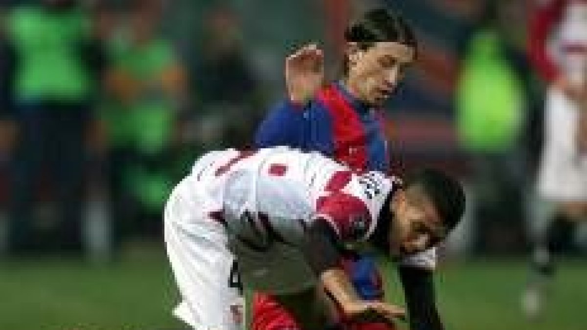 Daniel Alves lucha por el balón con Ovidiu Petre