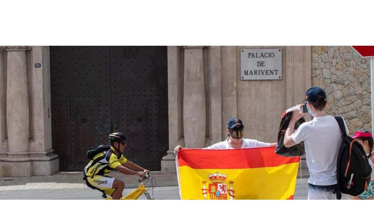 Un hombre se fotografía con la bandera de España ante la puerta principal del Palacio de Marivent, en Palma de Mallorca. CATI CLADERA
