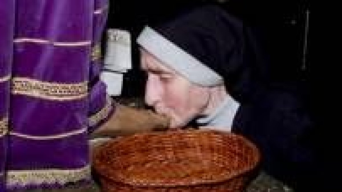 La religiosa mayor de la comunidad benedictina besa el pie del Cristo, en el besapiés