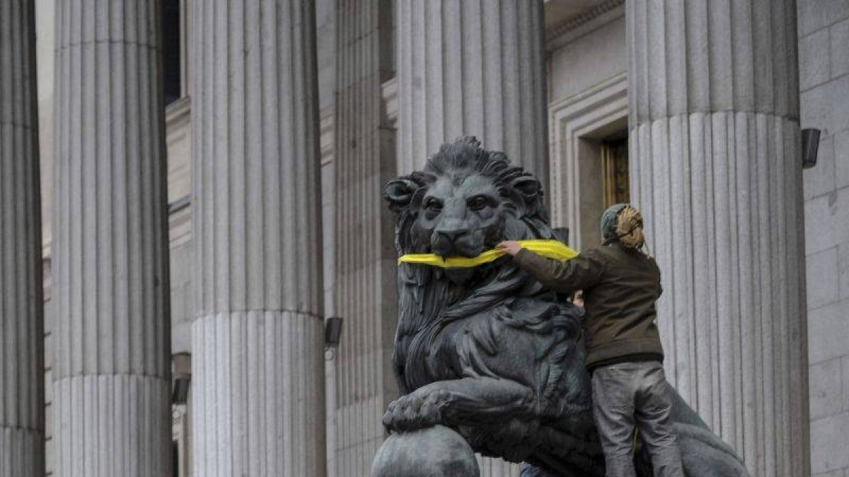 Una activista de Greenpeace amordaza los leones del Congreso de los Diputados.