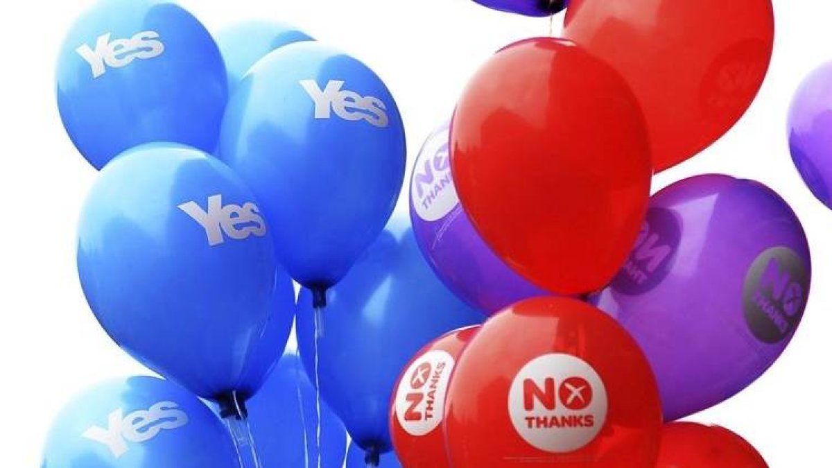 Partidarios del Sí y del No sujetan globos con distintos mensajes de cara al referéndum en Glasgow, ayer.