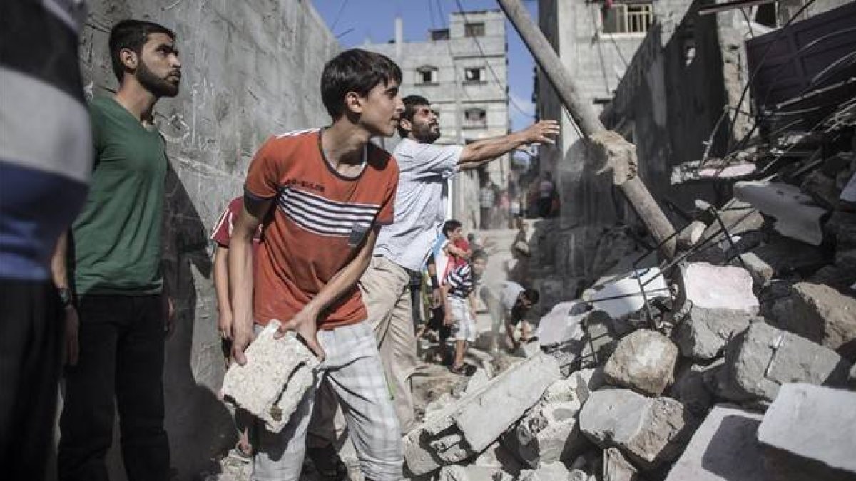 Unos palestinos trabajan en la retirada de escombros de una casa destruida por un bombardeo israelí, en Rafá, en el sur de Gaza, este martes.