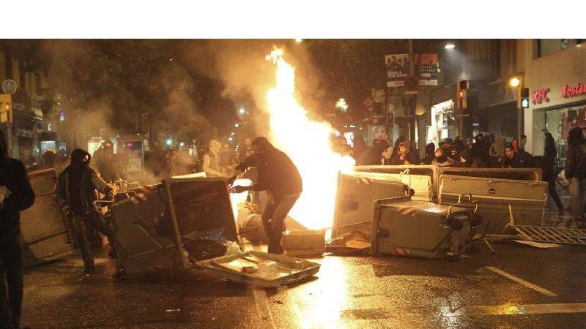 Varios jóvenes vuelcan y queman contenedores formando barricadas durante los incidentes producidos tras la manifestación llevada a cabo en el barrio de Sants de Barcelona.