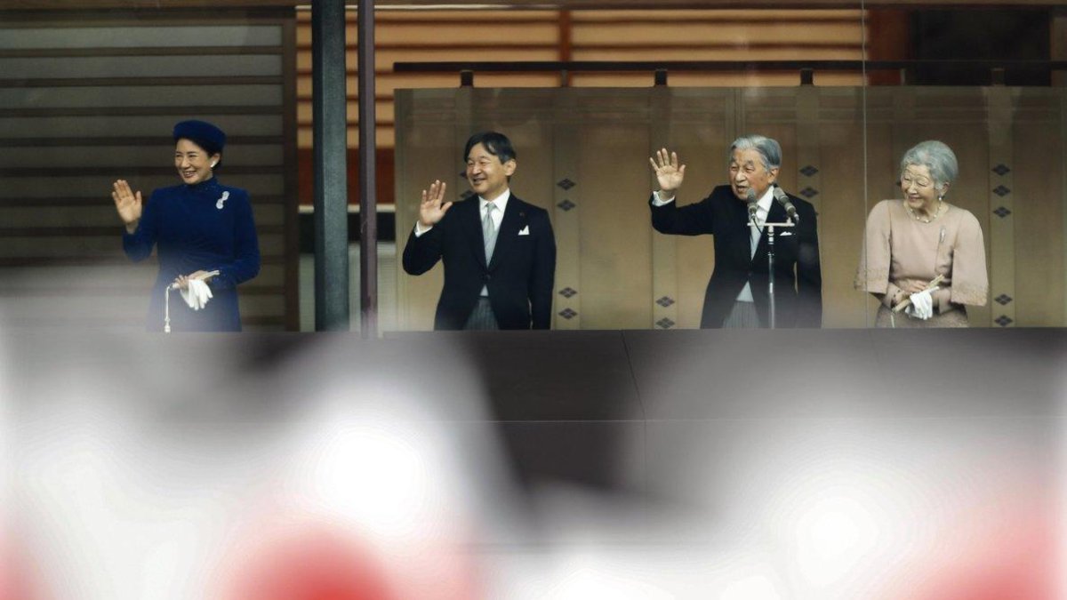 Emperor Akihito  waves to national flag-waving well-wishers with Empress Michiko,  Crown Prince Naruhito and Crown Princess Masako after delivering his speech marking his 85th birthday  his last birthday on the throne  at the Imperial Palace in Tokyo