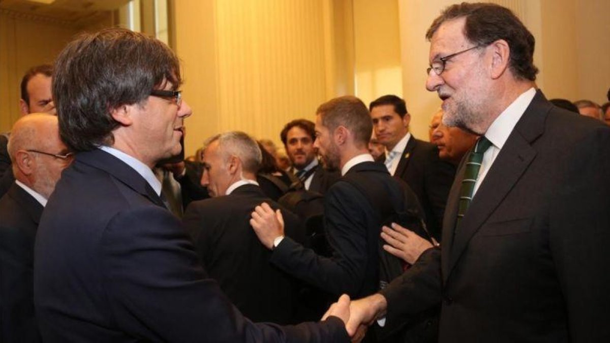 Puigdemont y Rajoy se saludan en el acto de inauguración de una exposición sobre Joan Miró en Oporto, el pasado septiembre.