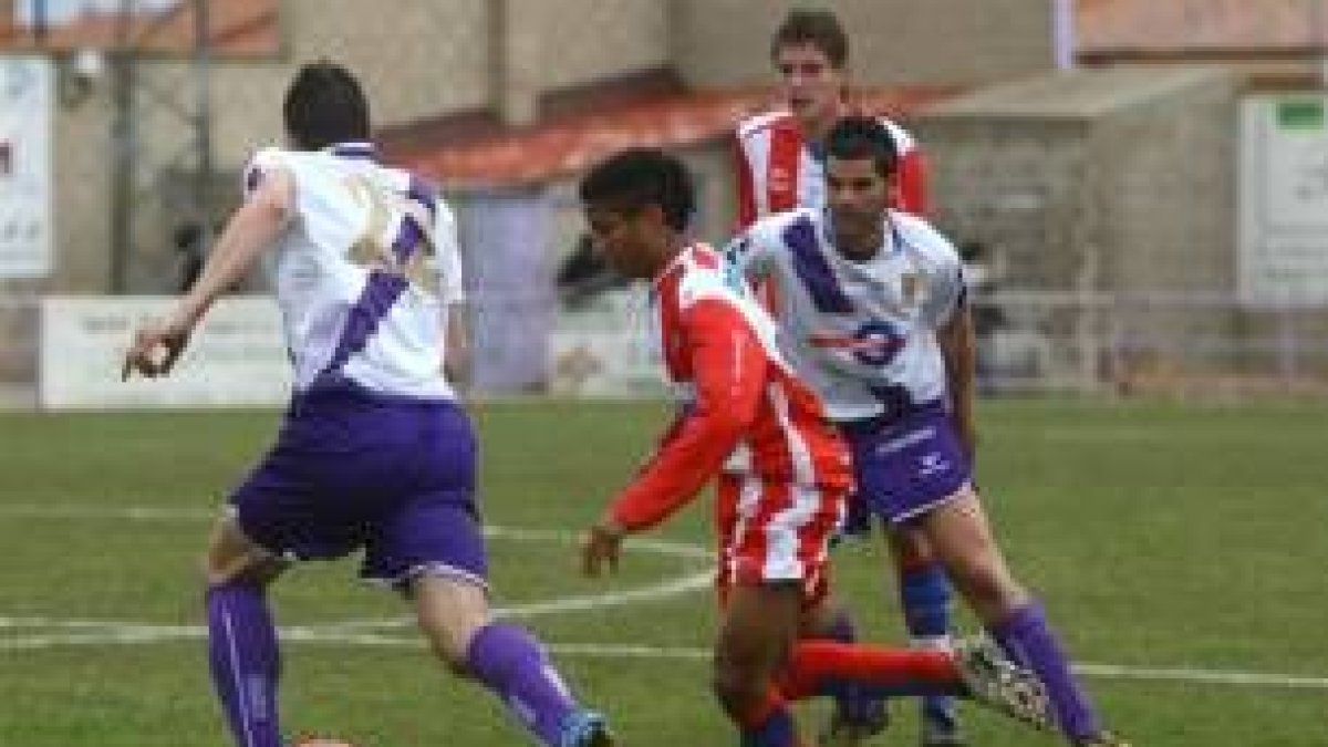 Mitogo conduce un balón y Moisés le observa en la distancia. Ambos debutaron con el primer equipo