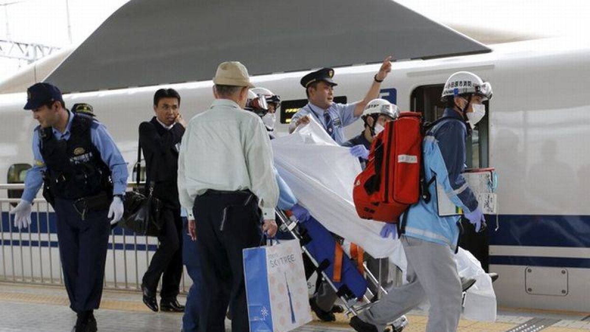 Un pasajero herido al suicidarse un individuo en un tren bala japonés es trasladado por los equipos de emergencia.