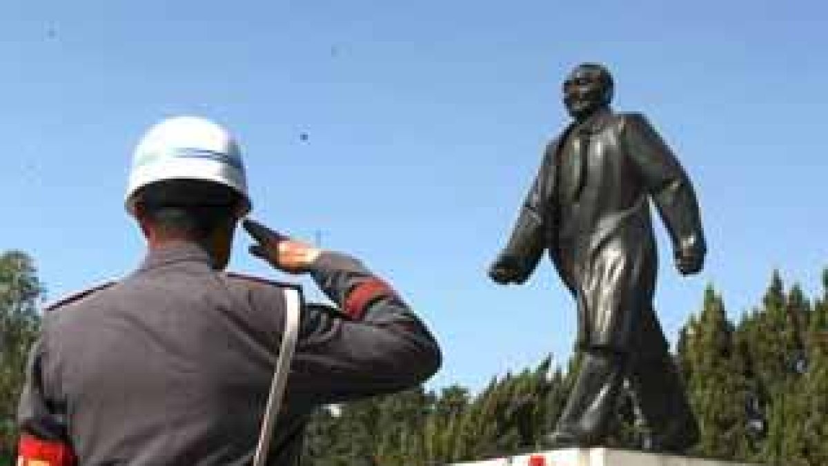 Dos guardas de seguridad saludan a la estatua del fallecido líder chino Deng Xiaoping.