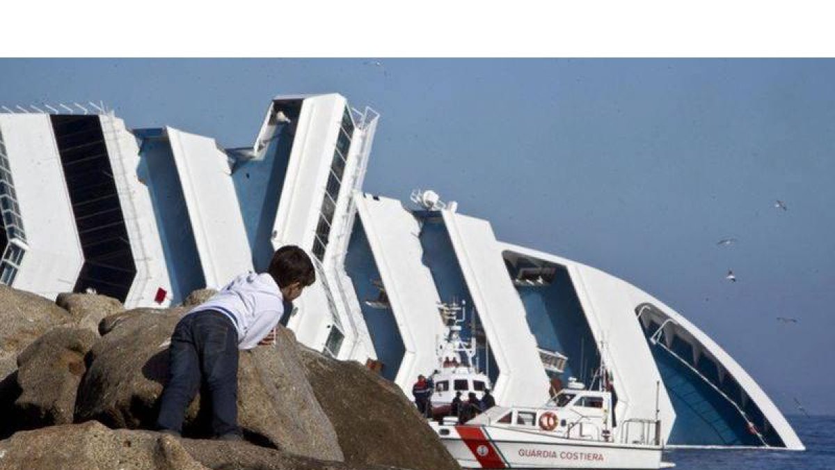 Un niño observa las lanchas de los guardacostas junto al crucero Costa Concordia, semihundido ante la isla de Giglio.