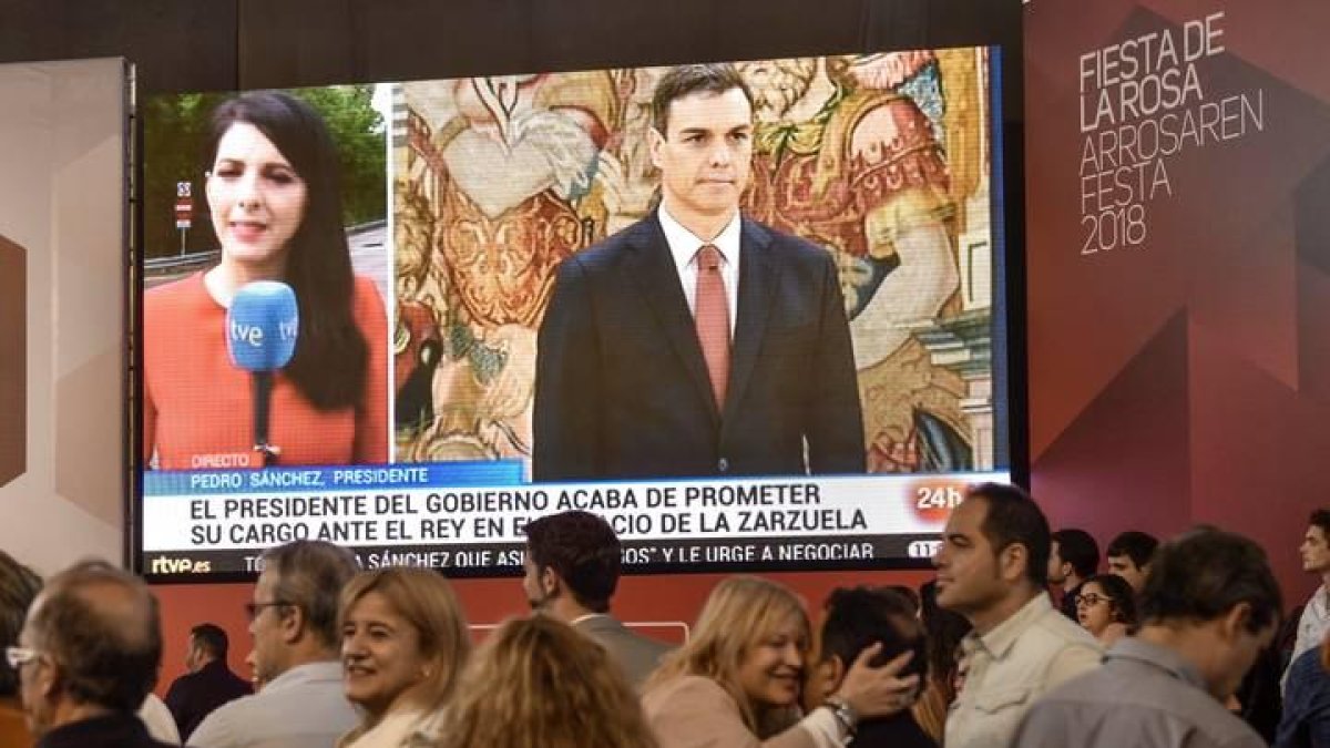 Los asistentes a la Fiesta de la Rosa celebrada en Durango, siguen desde una pantalla a Pedro Sánchez en el acto el sábado  en el que ha prometido su cargo como presidente del Gobierno.