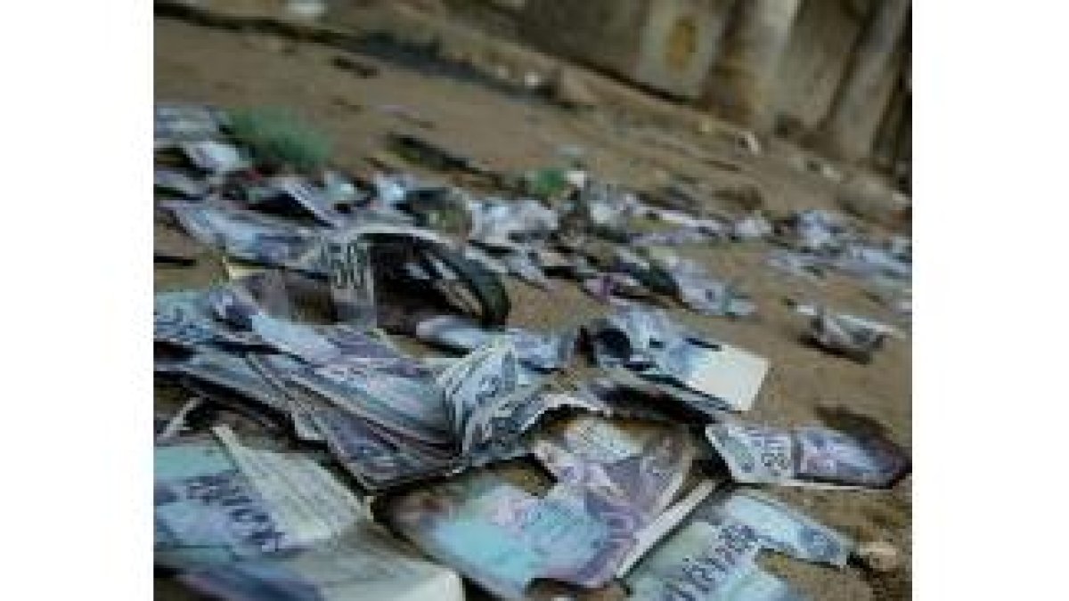 Billetes con la cara de Sadam Husein reposan en el suelo en uno de los saqueos en Bagdad