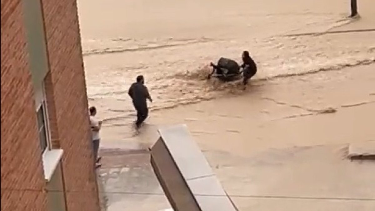 La mujer intenta cruzar la riada antes de que el pequeño se caiga del carrito. DL