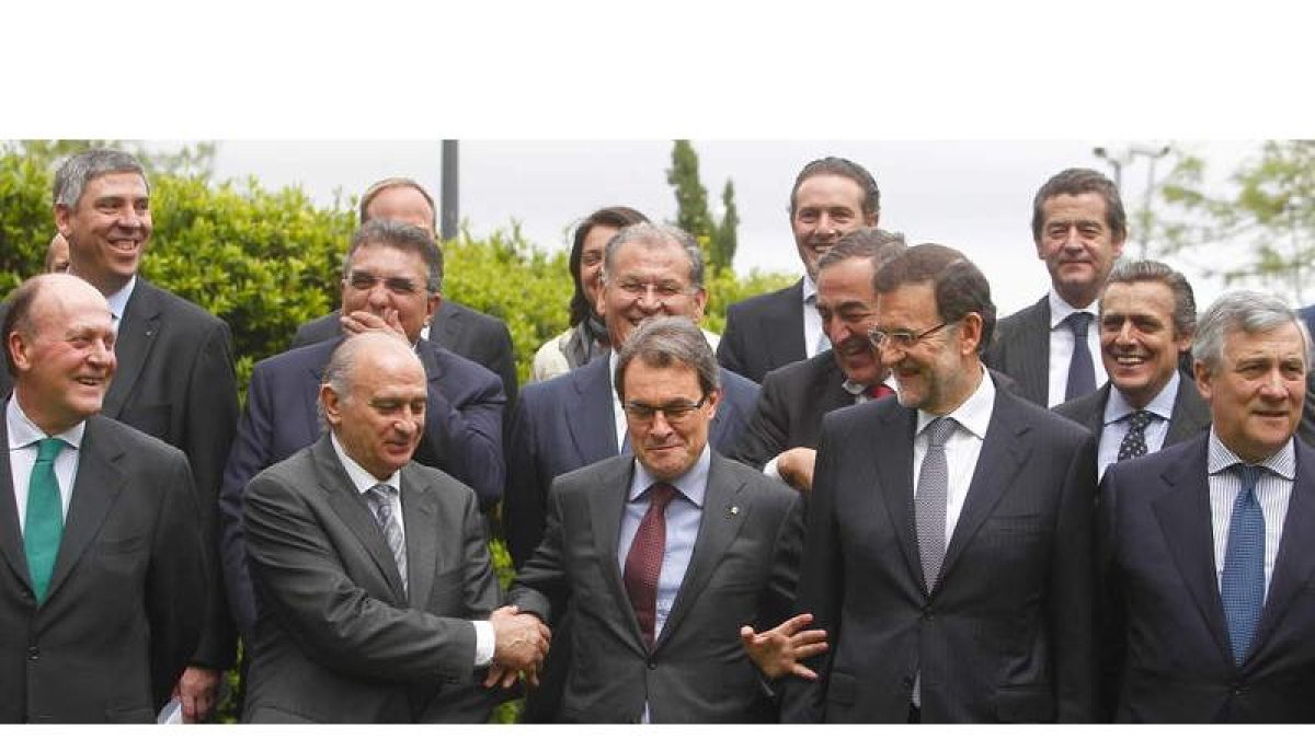 El ministro del Interior, Jorge Fernández Díaz, estrecha la mano del presidente de la Generalitat, Artur Mas, en presencia de Mariano Rajoy.
