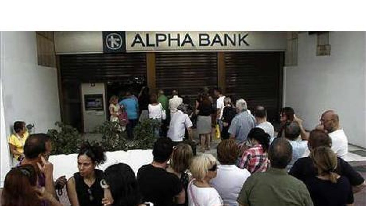 Decenas de personas hacen cola para sacar dinero de un banco en Atenas.