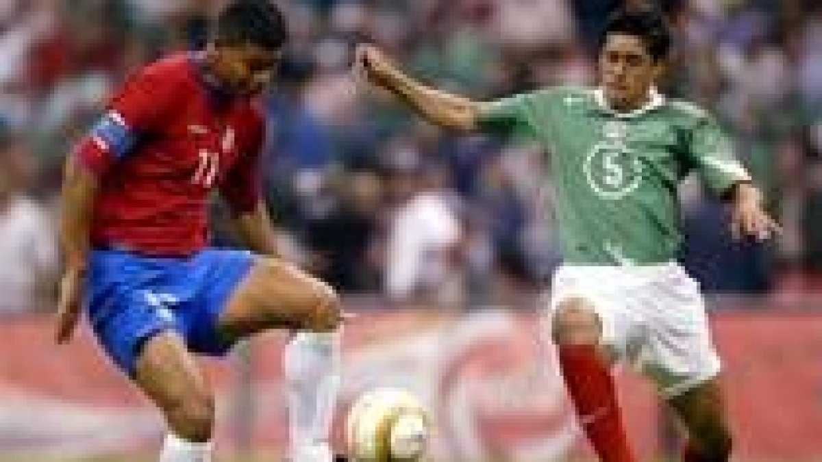El costarricense Ronald Gómez y el defensa mexicano Ricardo Osorio pelean por un balón