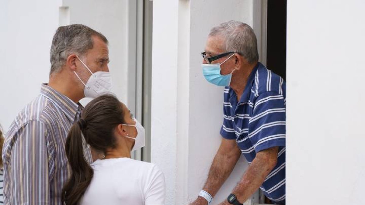 Los reyes Felipe VI y Letizia conversan con un vecino mientras visitan este jueves en el acuartelamiento El Fuerte, donde se alojan familias evacuadas por la erupción de La Palma. RAMÓN DE LA ROCHA