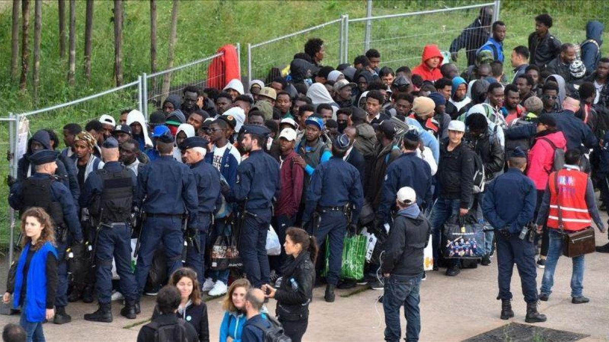 Policías franceses escoltan a los refugiados que han sido desalojados del campamento cercano a París.