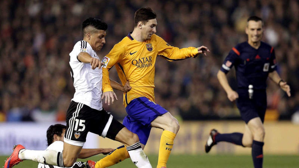 Leo Messi se lleva el balón ante el acoso de los jugadores del Valencia Enzo Pérez y Parejo