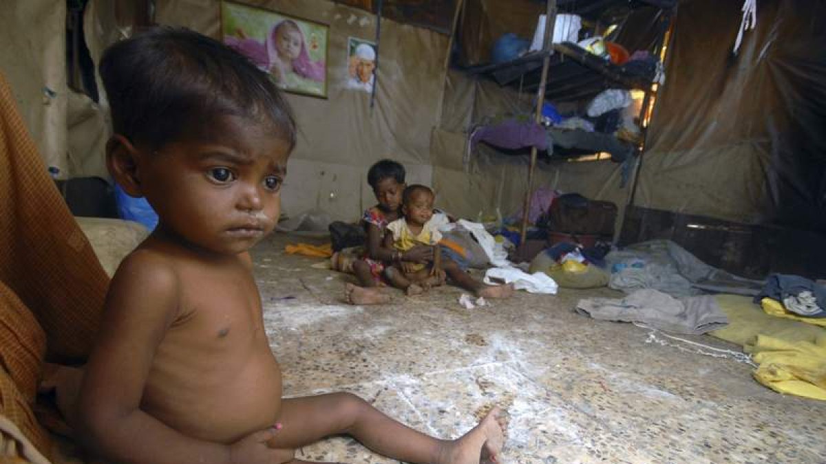 Un niño desnutrido espera sentado en una chabola en Bombay.