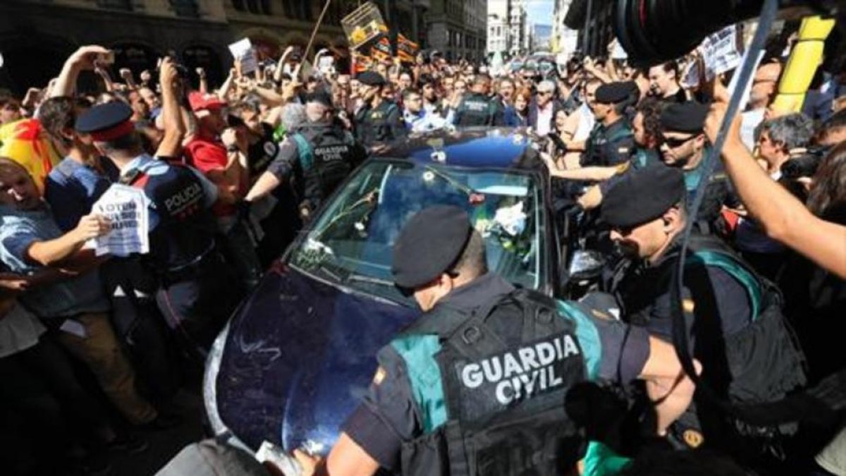 Mossos ayudan a guardias civiles a salir de una concentración de protesta ante la Conselleria dAfers Exteriors.