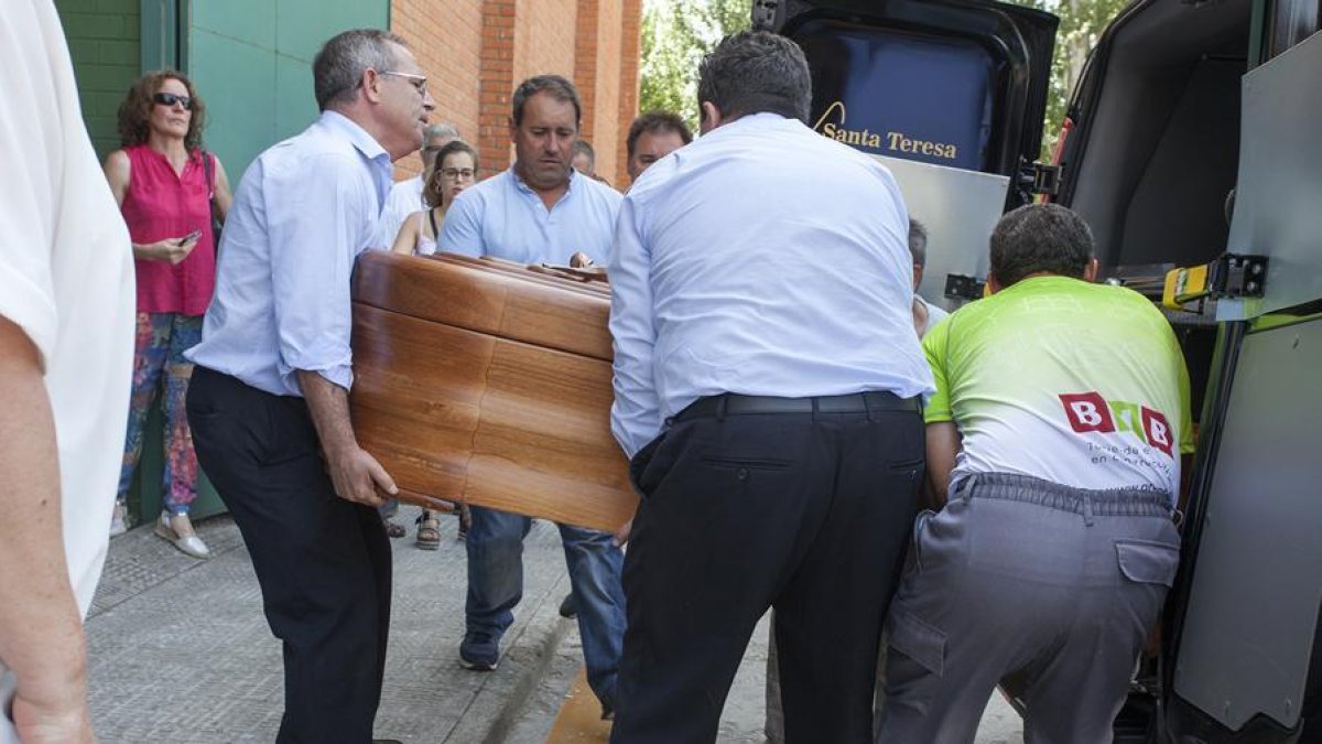 Los servicios funerarios extraen el féretro de uno de los fallecidos a su llegada al municipio de Alba de Tormes.