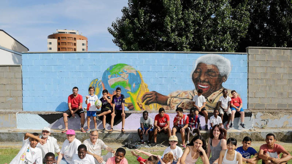 Niños y niñas de la asociación Auryn posan junto al mural pintado por Diego Fidalgo. SECUNDINO PÉREZ