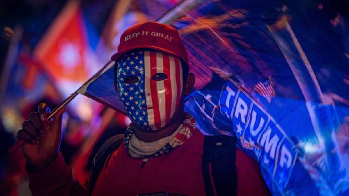 Un simpatizante de Donald Trump viste careta con la bandera estadounidense y una gorra que dice «Mantén (América) grandiosa» en Miami. GIORGIO VIERA