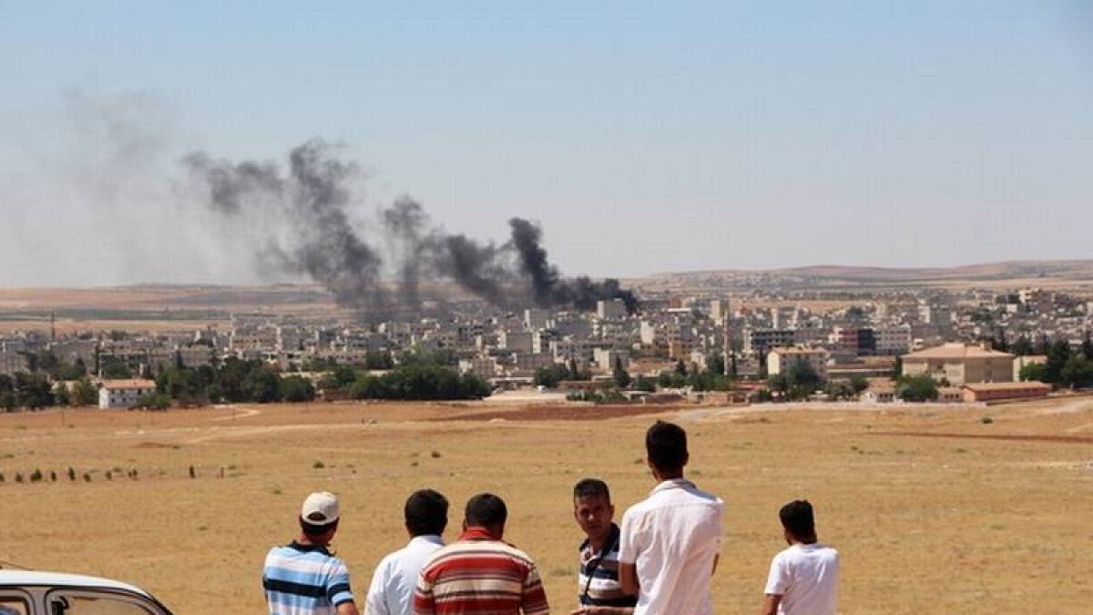 Gente mira el humo de los combates en Kobane desde la frontera turca.