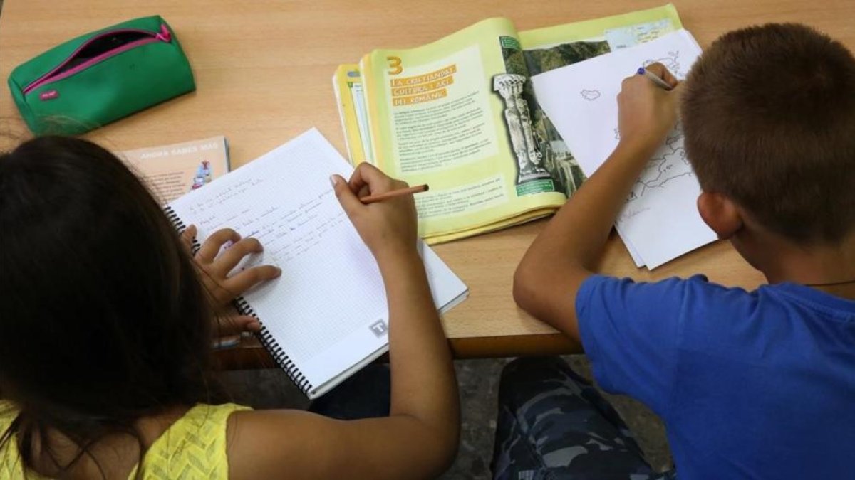 Dos niños de primaria haciendo deberes en su casa, después del colegio.