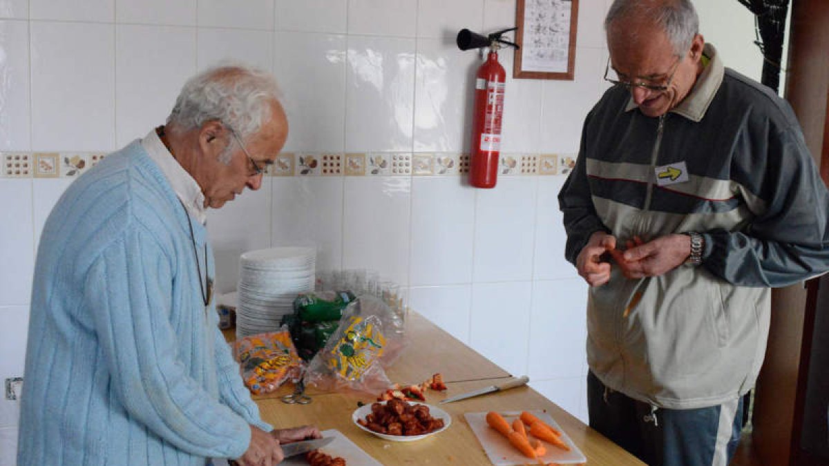 Ramón Herguedas prepara la comida en el albergue junto a un peregrino.