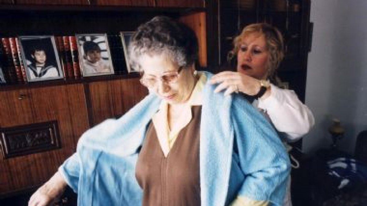 Una anciana es ayudada por una enfermera integrante del servicio de asistencia a domicilio