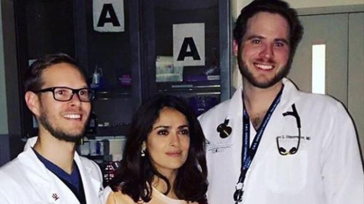 Salma Hayek, con la camiseta que representa unas manos cogiéndole los pechos, posa con los doctores que la han atendido de urgencia en el hospital.