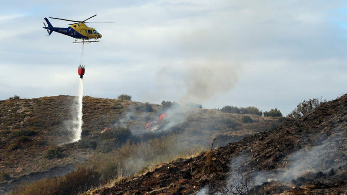 Las descargas de agua de un helicóptero ayudaron a controlar ayer el incendio en la linde del Camino de Santiago en El Acebo. BARREDO