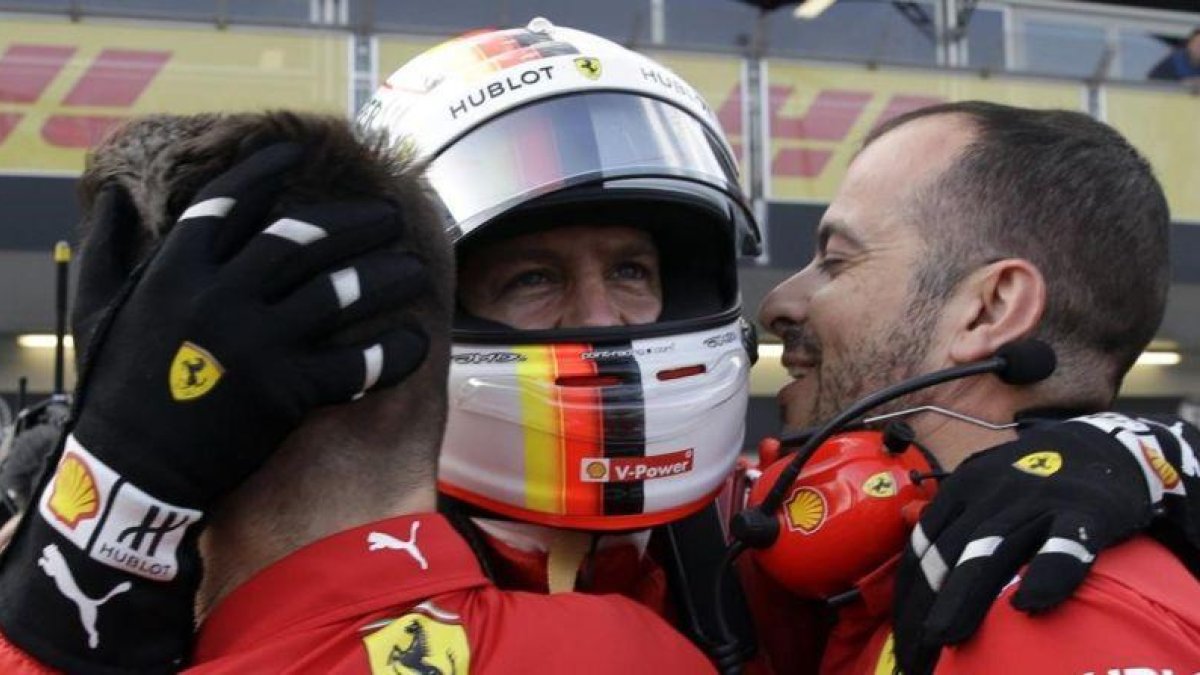 Sebastian Vettel es felicitado por dos de sus mecánicos tras lograr su tercera pole consecutiva de la temporada.