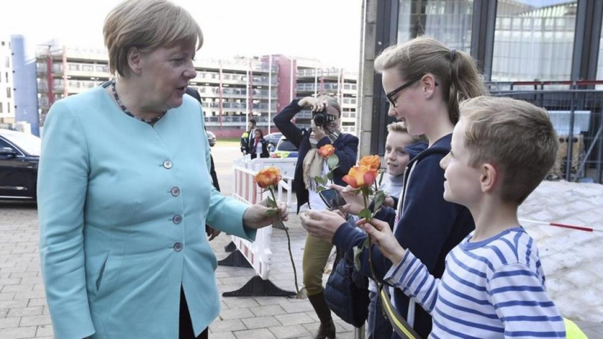 La cancillera Merkel, recibida con ramos de flores de niños a su llegada al Parlamento regional de Dusseldorf, con motivo del 70 aniversario de la CDU, el 30 de septiembre.
