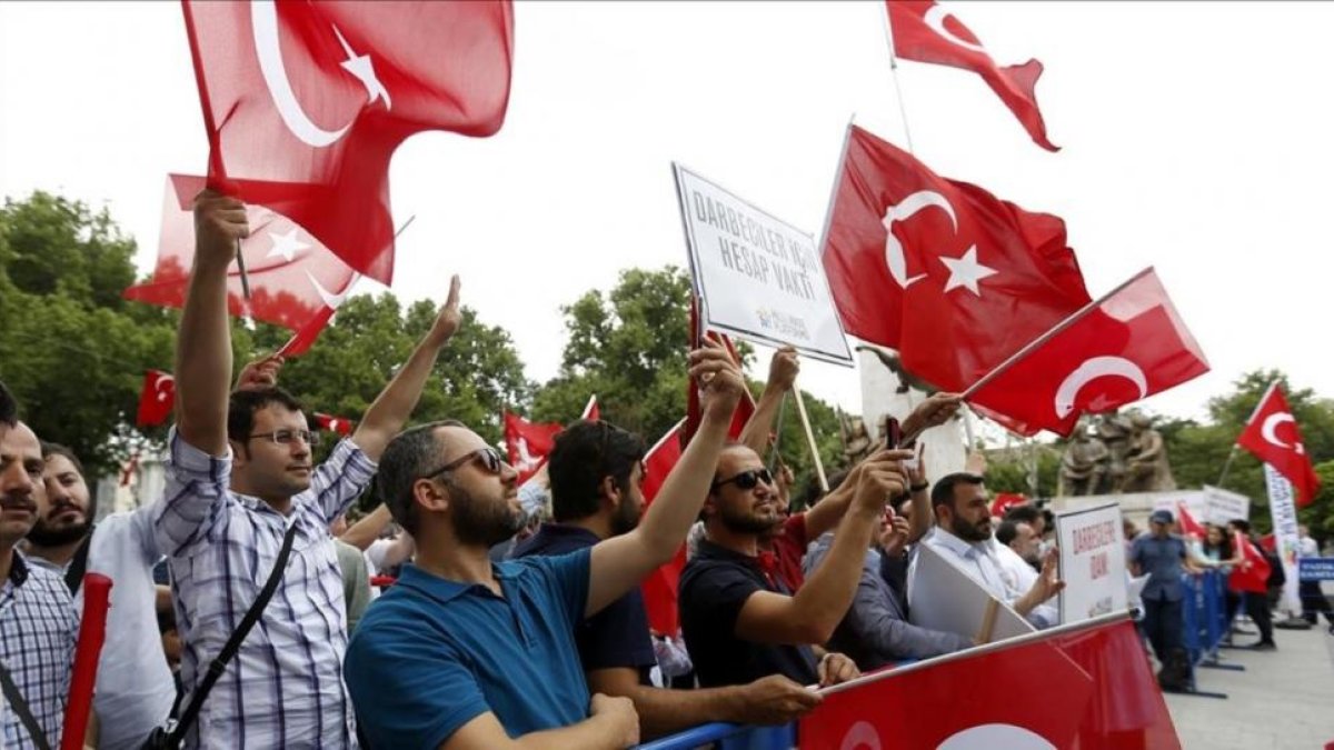 Ciudadanos turcos ondean banderas de su país durante una protesta en la víspera del primer aniversario del fallido golpe de Estado.