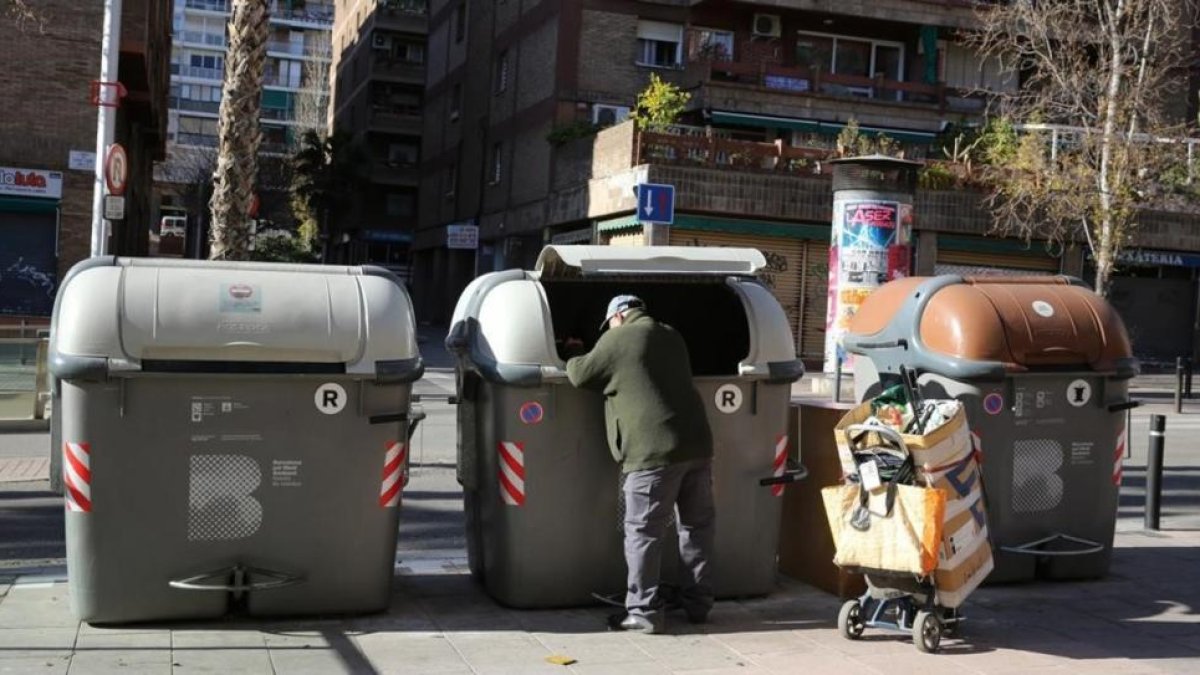 Un hombre recoge basura en unos contenedores