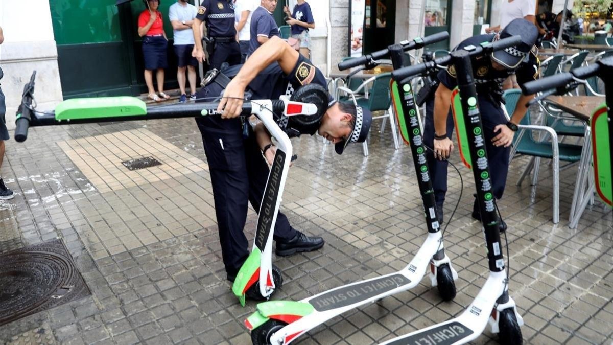 Agentes de la policía local de Valencia retiran unos patinetes eléctricos de alquiler.