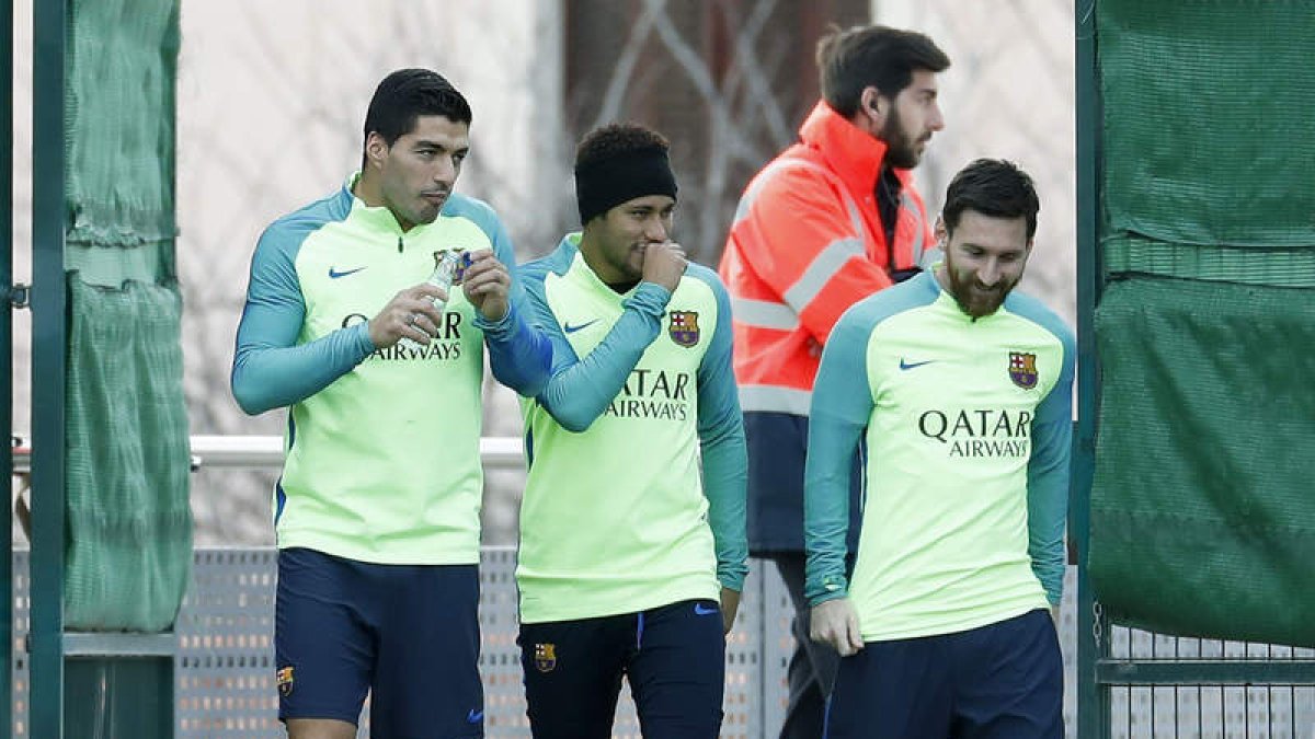 Luis Suárez, Neymar y Leo Messi entran al campo para participar en el entrenamiento de ayer. DALMAU