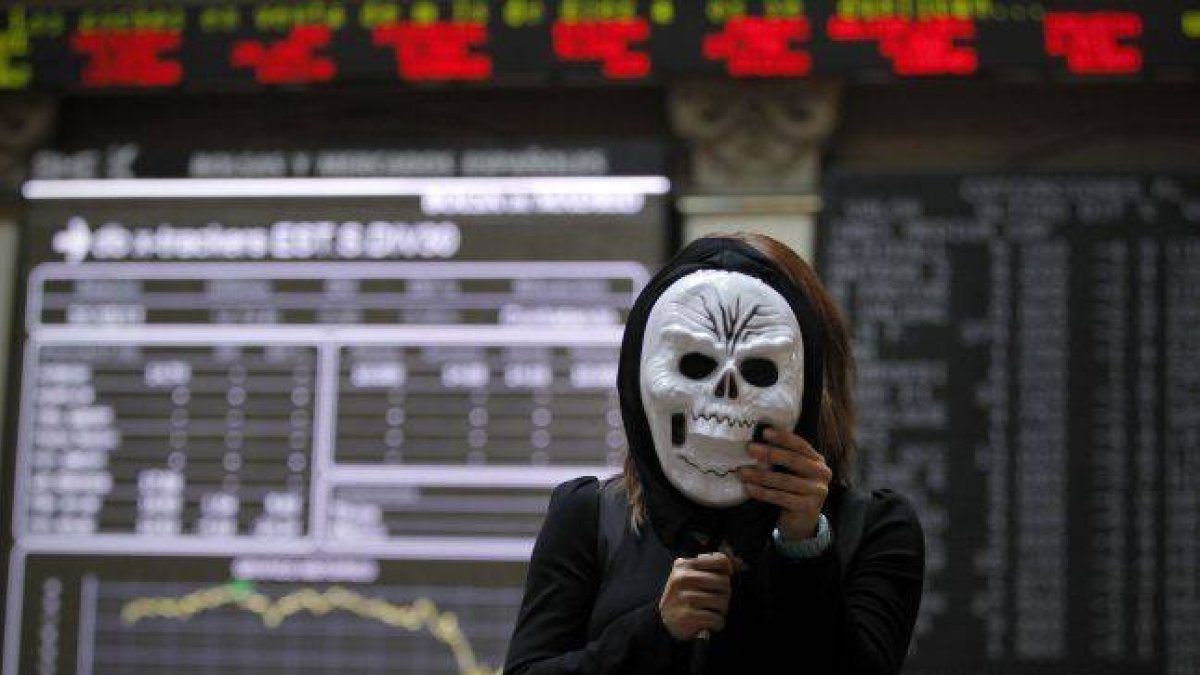 Bolsa de Madrid, hoy. En la imagen una periodista realiza una conexion en directo con una mascara de Halloween.