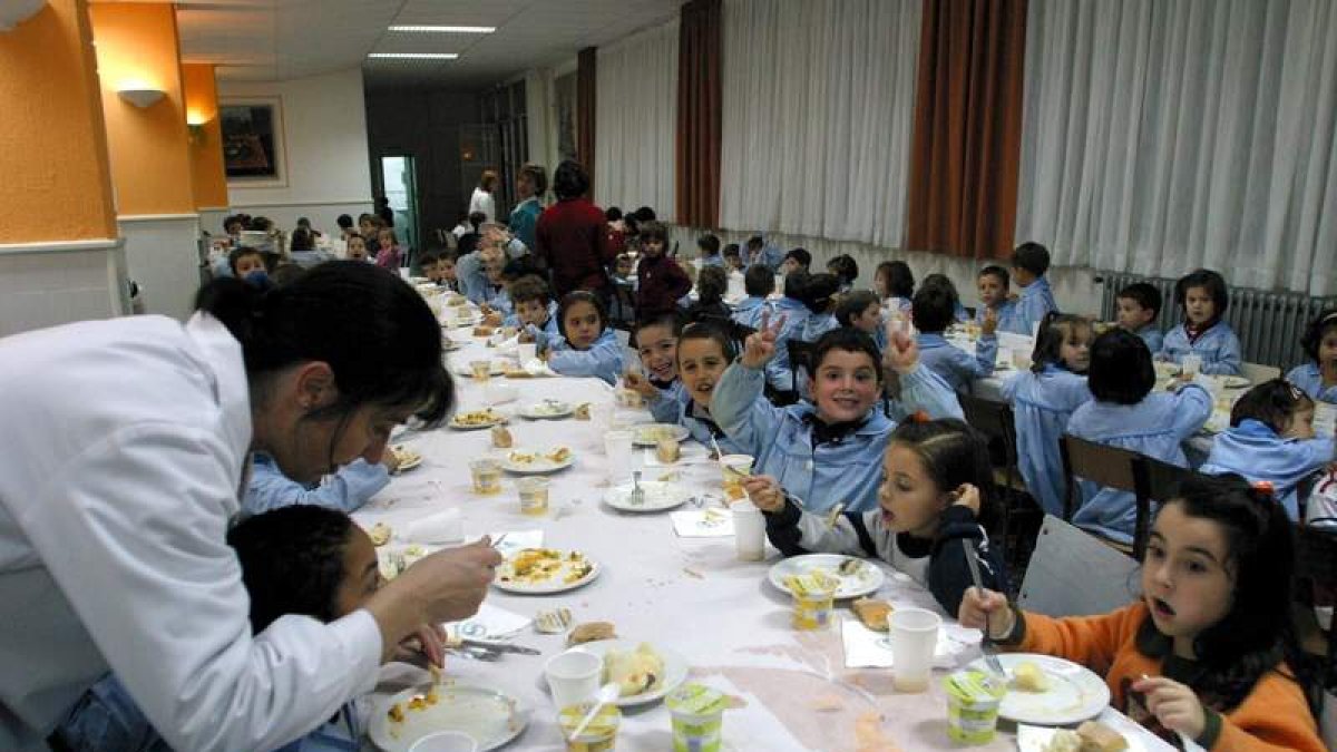 Una cuidadora ayuda a un niño a comer en un centro escolar.