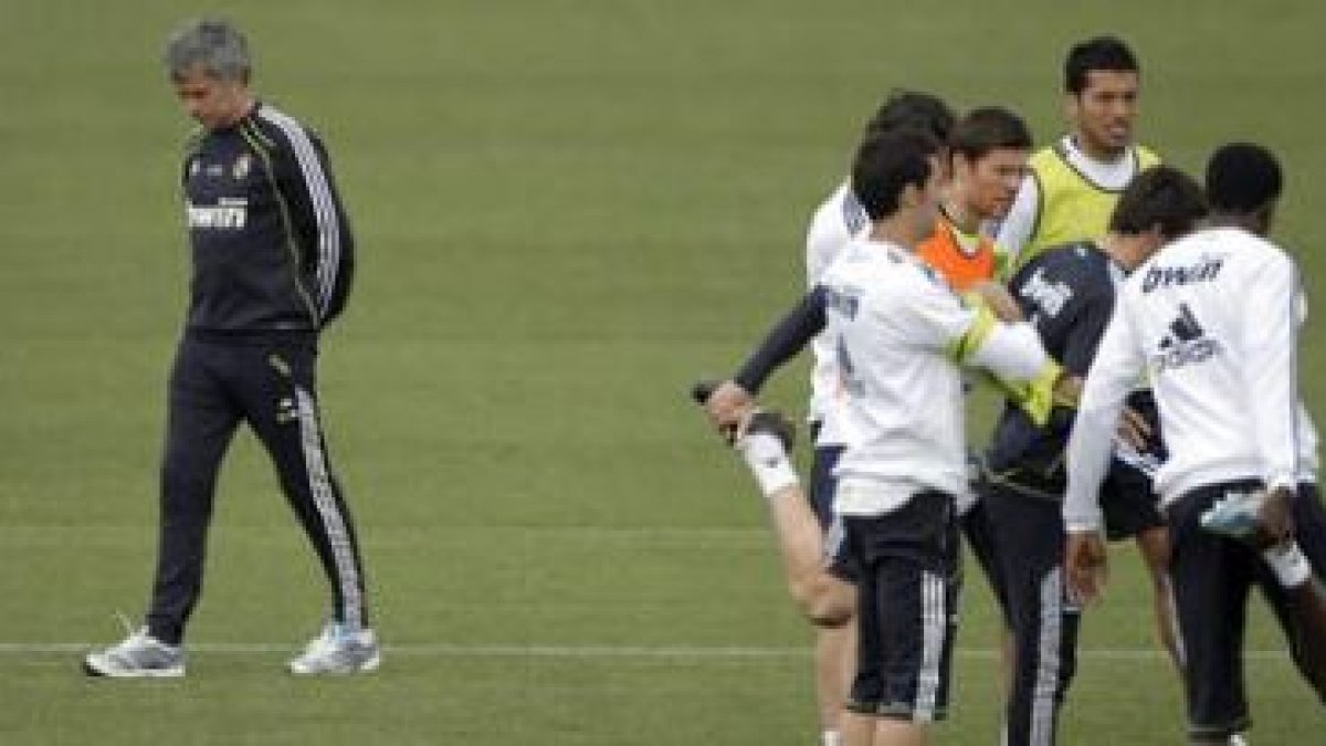 El técnico José Mourinho, pasa junto a varios de sus jugadores, durante el entrenamiento de ayer.