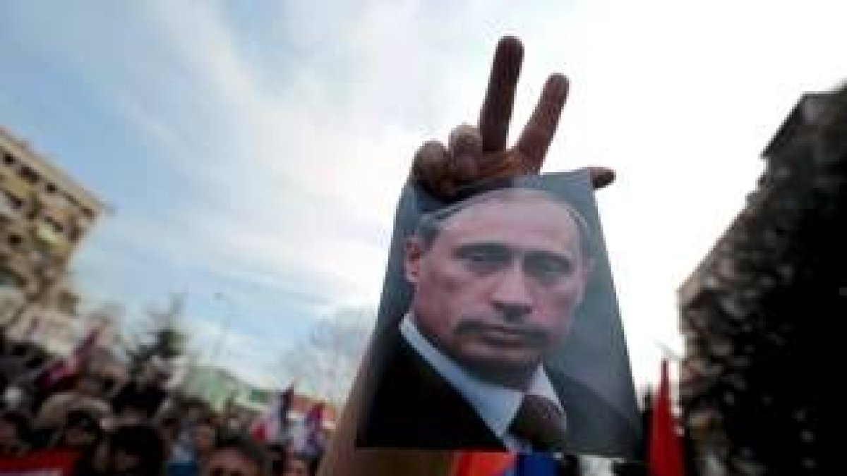 Un ciudadano serbio de Kosovo alza una imagen de Putin junto al signo de la victoria