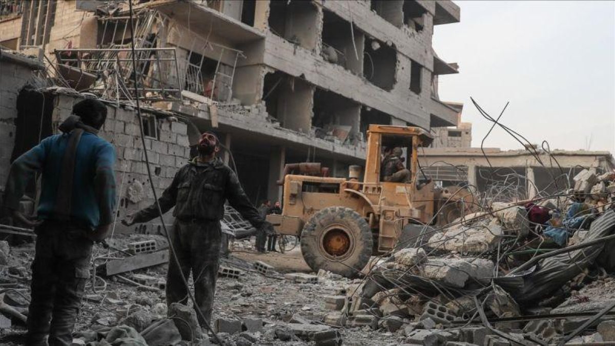Civiles y voluntarios de la Defensa Civil Siria buscan sobrevivientes tras varios ataques aéreos en la ciudad de Hamoria, en Guta.