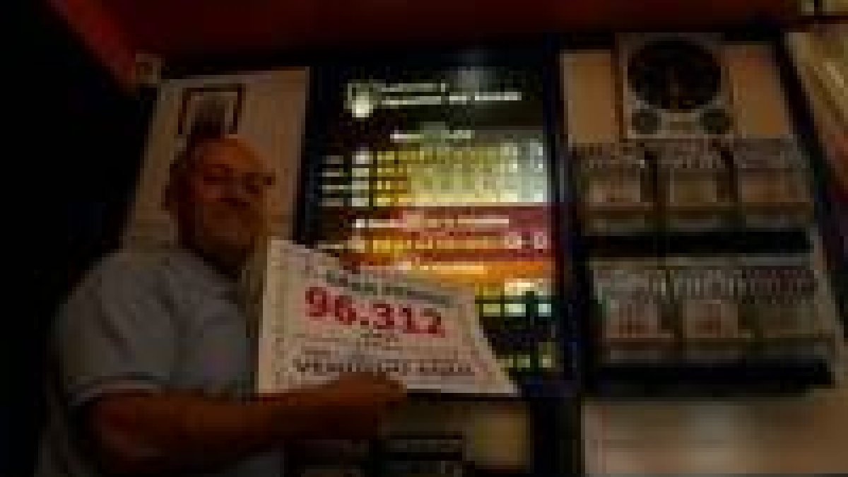 El propietario del bar Las Eras de Camponaraya mostrando el cartel del número premiado
