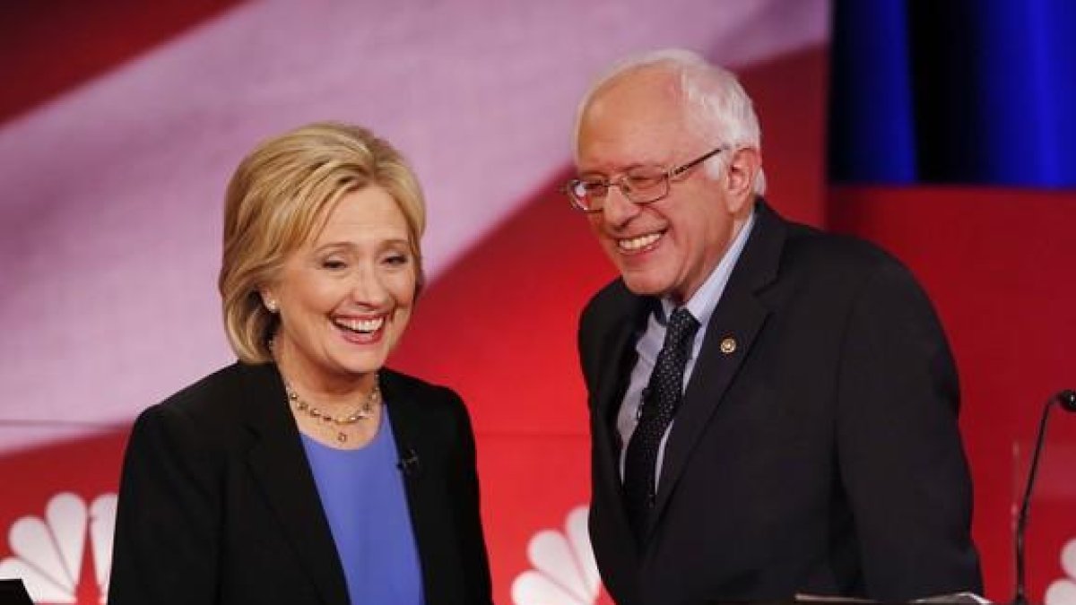 Hillary Clinton y Bernie Sanders sonríen durante una pausa del debate de candidatos demócratas, el domingo en Charleston.
