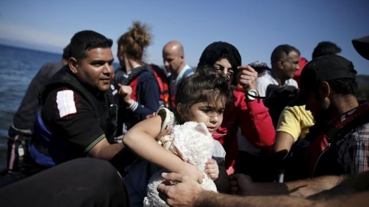 Una niña siria es ayudada a bajar de su embarcación en la isla griega de Lesbos, este sábado.