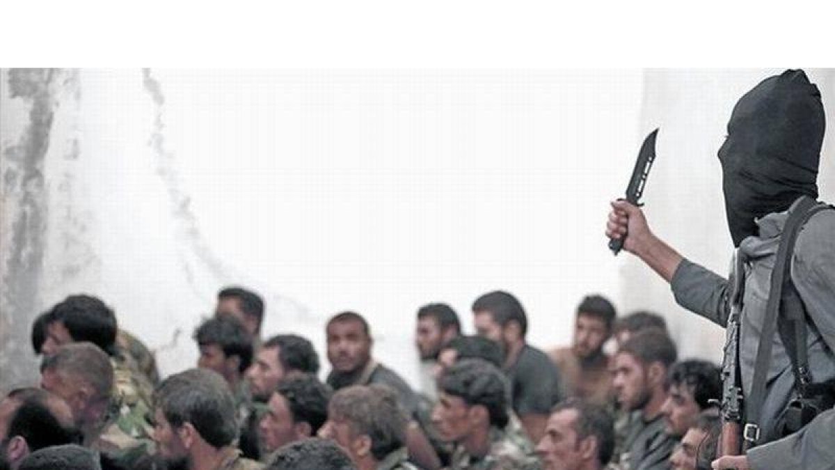 Combatiente del Estado Islámico junto a soldados sirios, tras la toma de una base cerca de Raqqa.