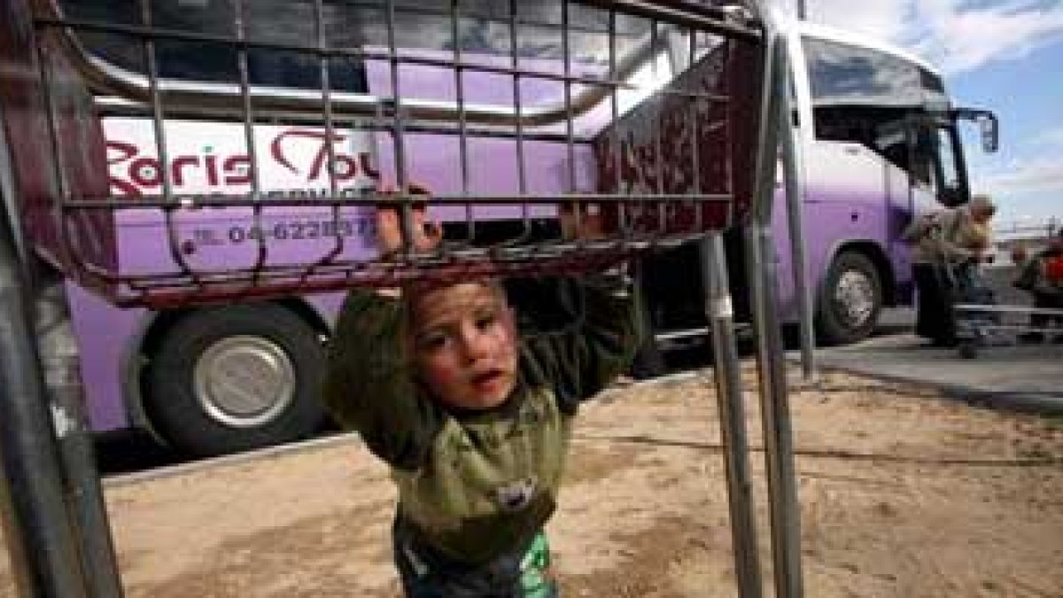 Un palestino juega mientras su familia carga sus pertenencias en un bus que los sacará de Gaza.